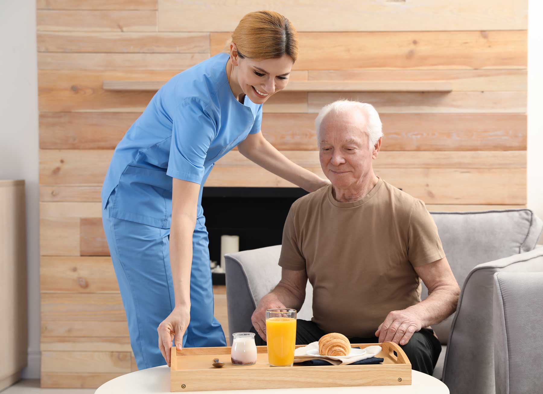 A home care attendant sets breakfast down before her senior client.